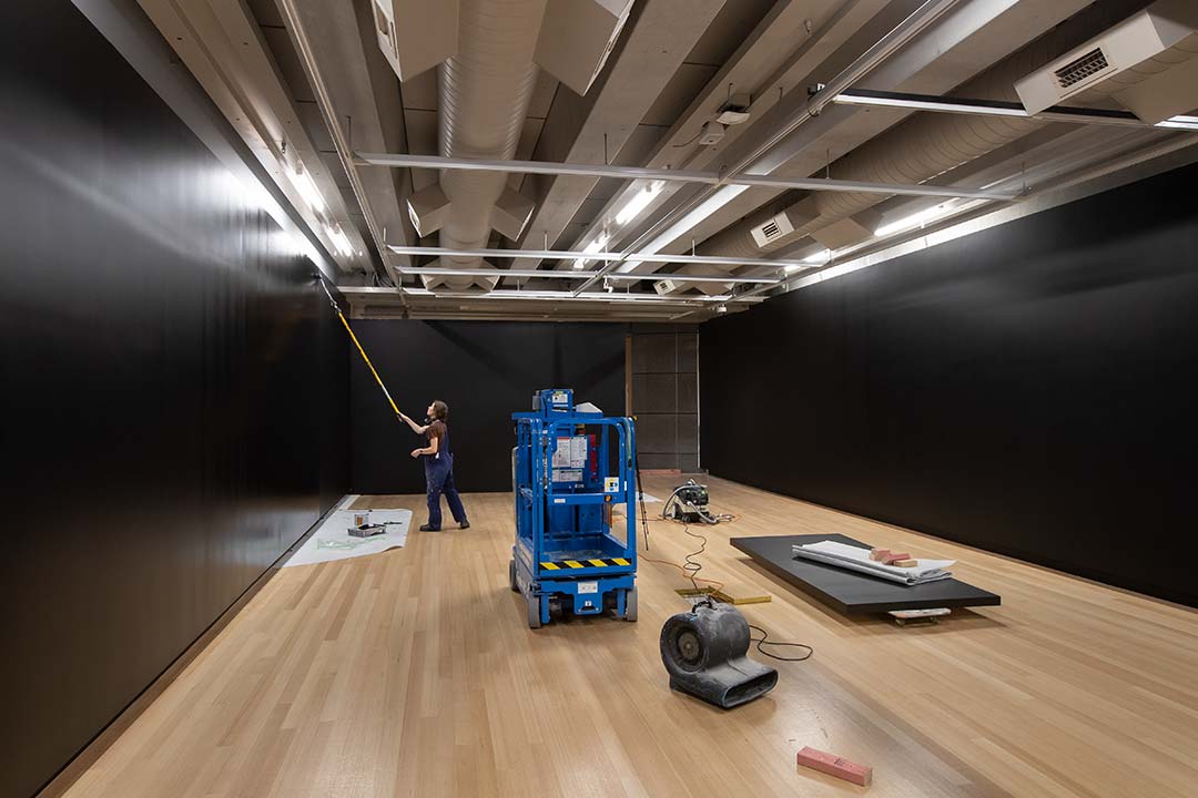 Man painting a gallery wall in black