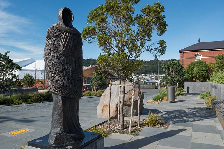 A bronze statue of a woman facing the National War Memorial.