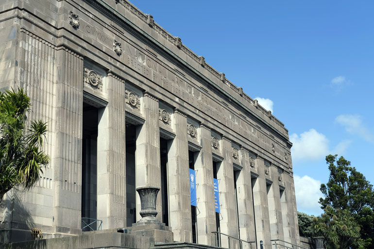 The front of the old Dominion Museum in Wellington. Grey stone building with columns.