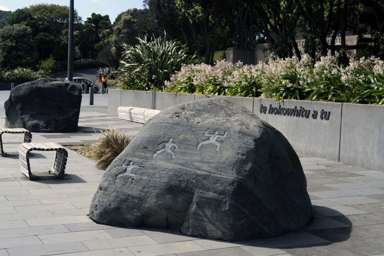 Two large stones with carvings in front of a garden.
