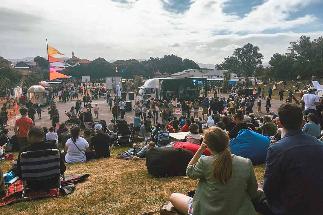 Crowds sitting outside on a grass bank at a music festival on Waitangi Day
