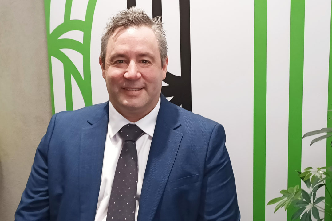 Man in a blue suit and tie in front of a white, green and black background