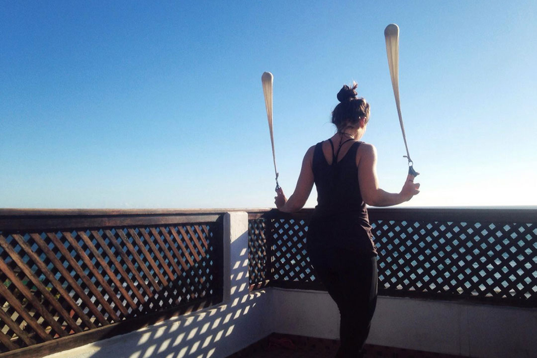 Woman on a deck swinging poi while facing out to sea