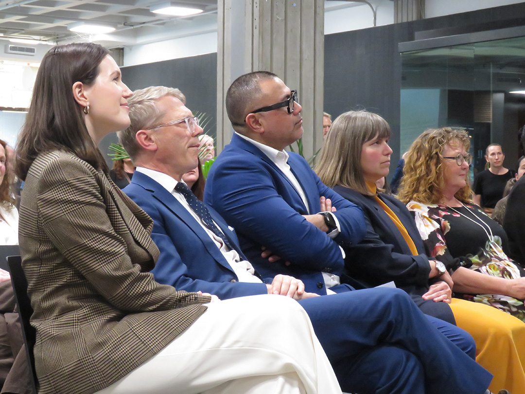 Ministers and others seated in crowd listening to speaker
