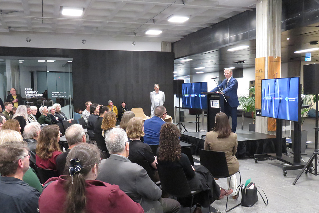 Minister standing at podium in front of crowd at City Gallery Wellington