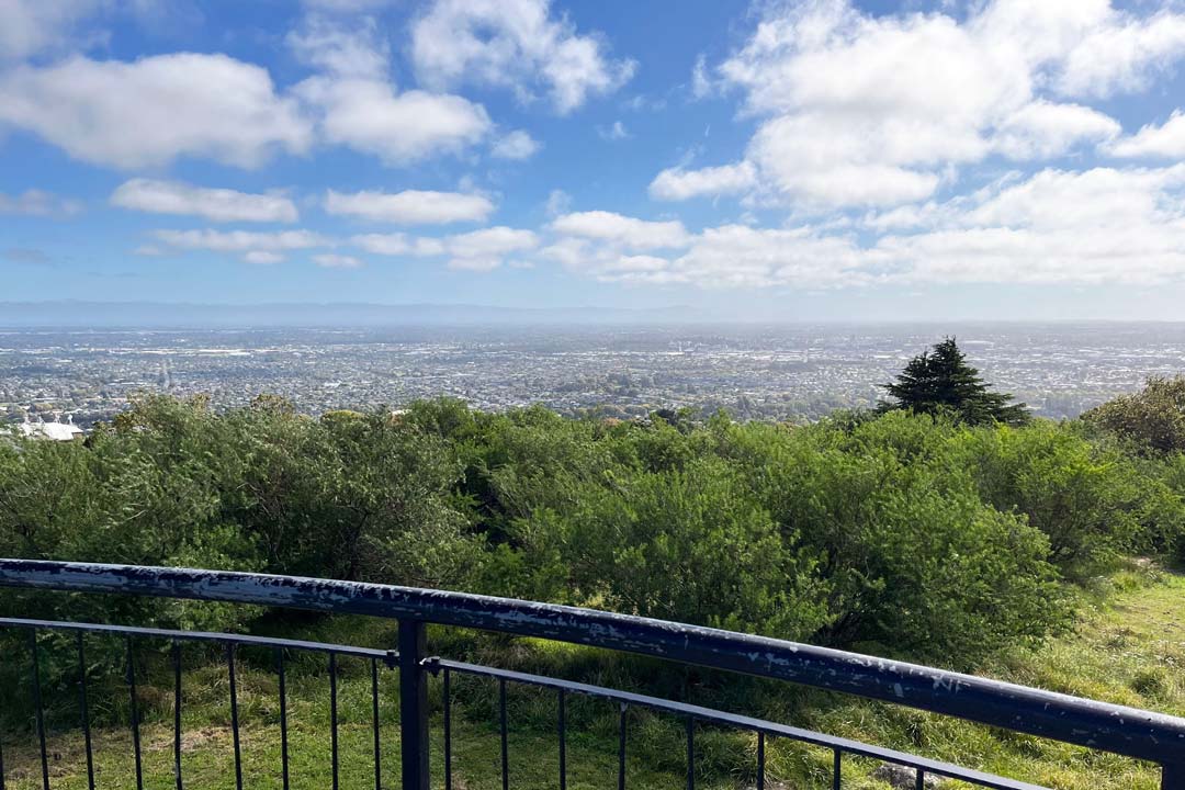 View from hill looking out over city and mountains in the distance