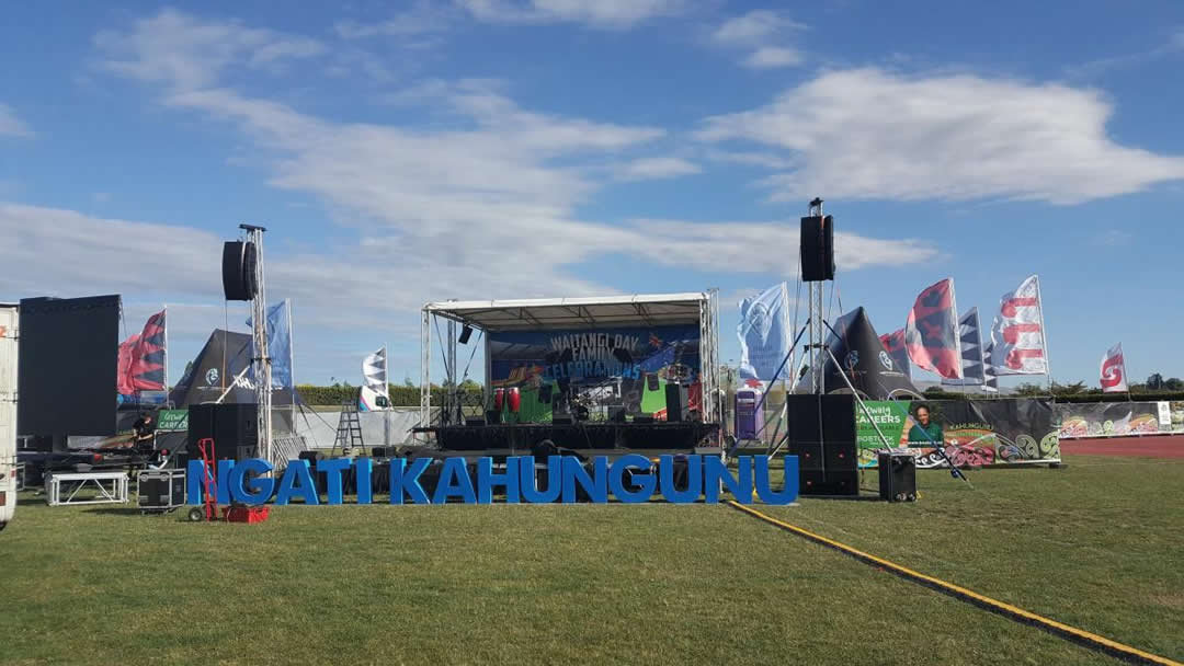 Blue letters spelling Ngati Kahungunu in front of stage on grass