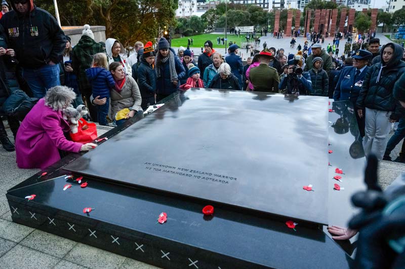Crowd gathered around the Tomb of the Unknown Warrior with poppies on it.