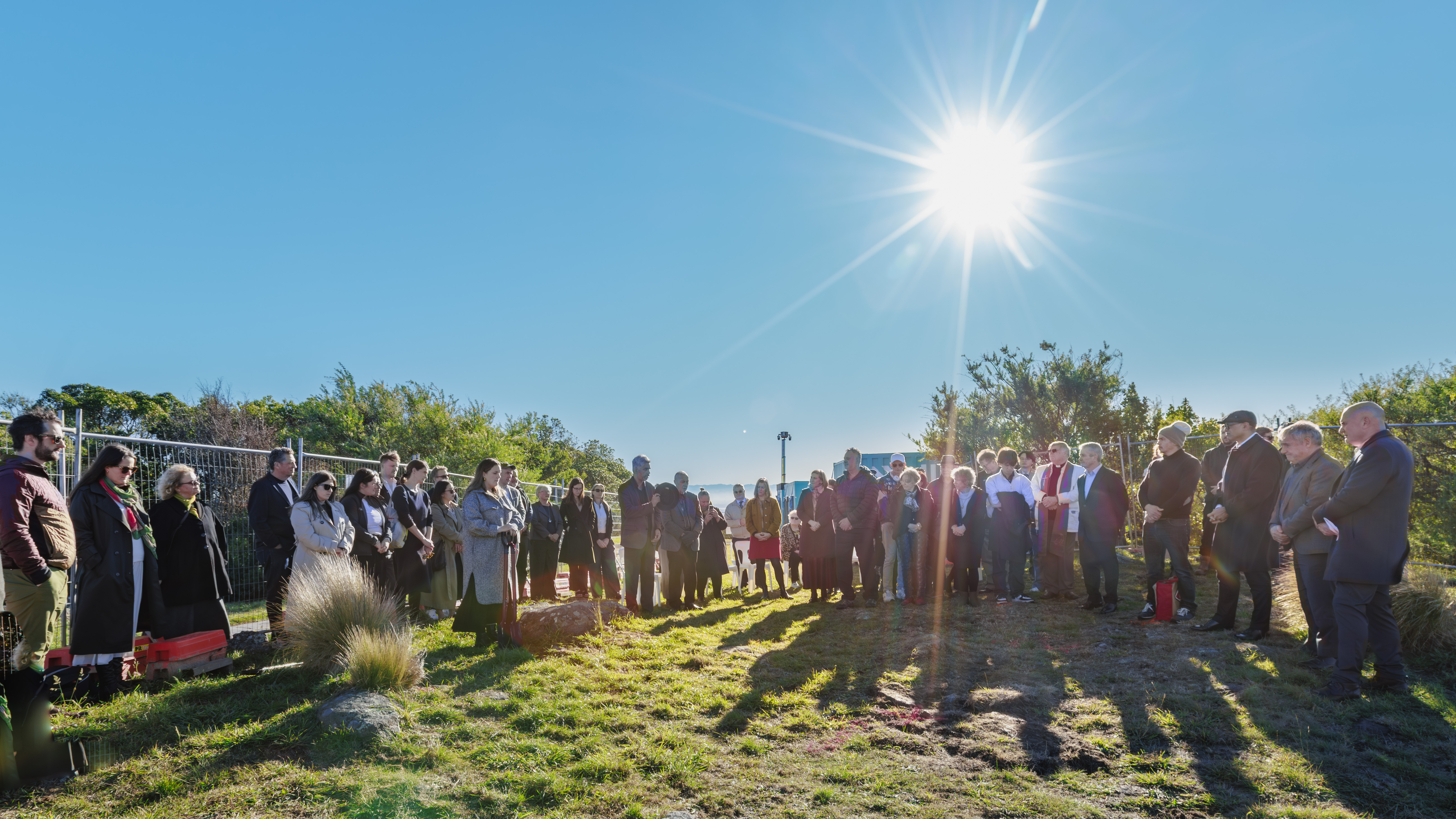 Crowd gathered in prayer on hill a sun rises in background
