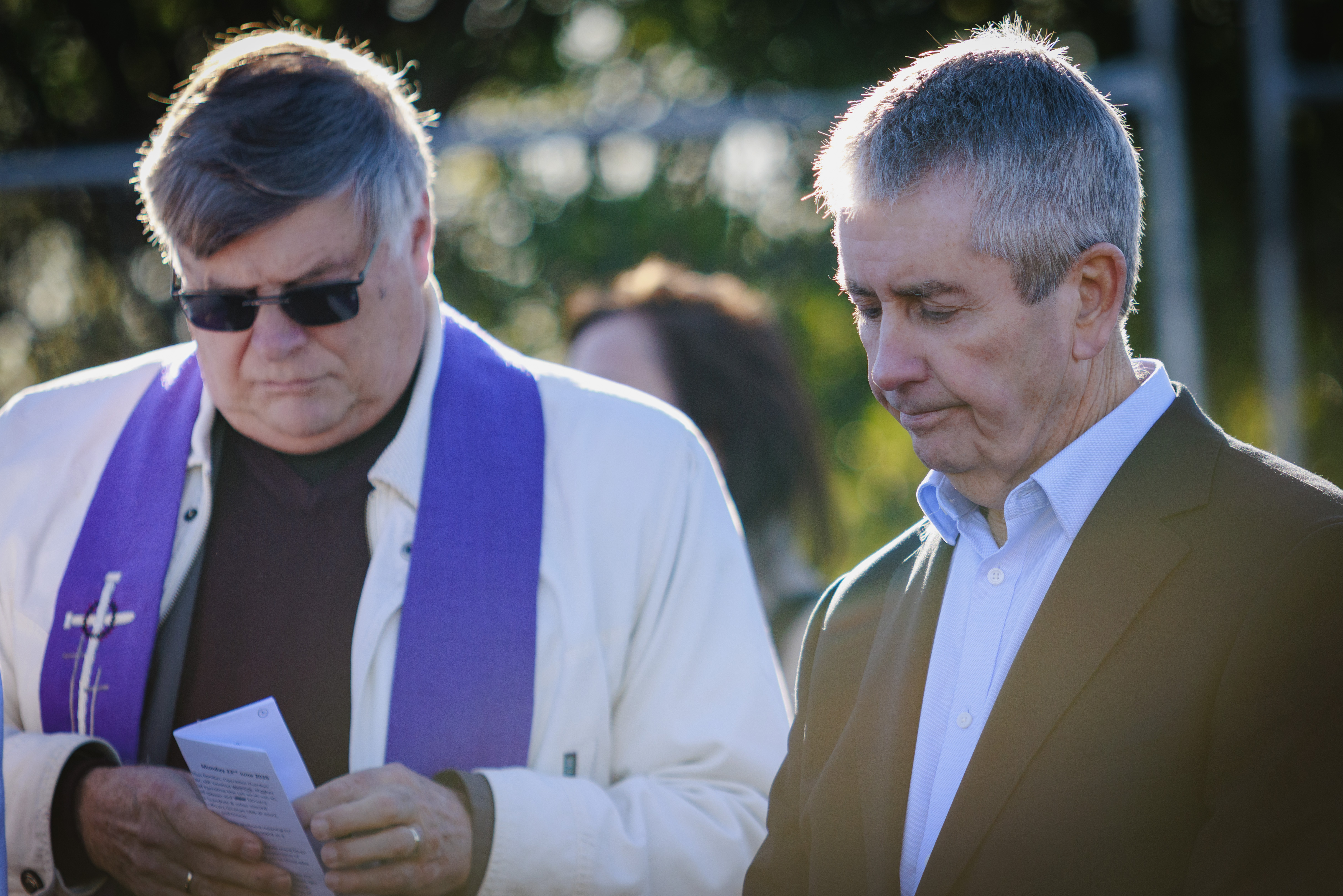 Priest and other man with heads bowed at ceremony