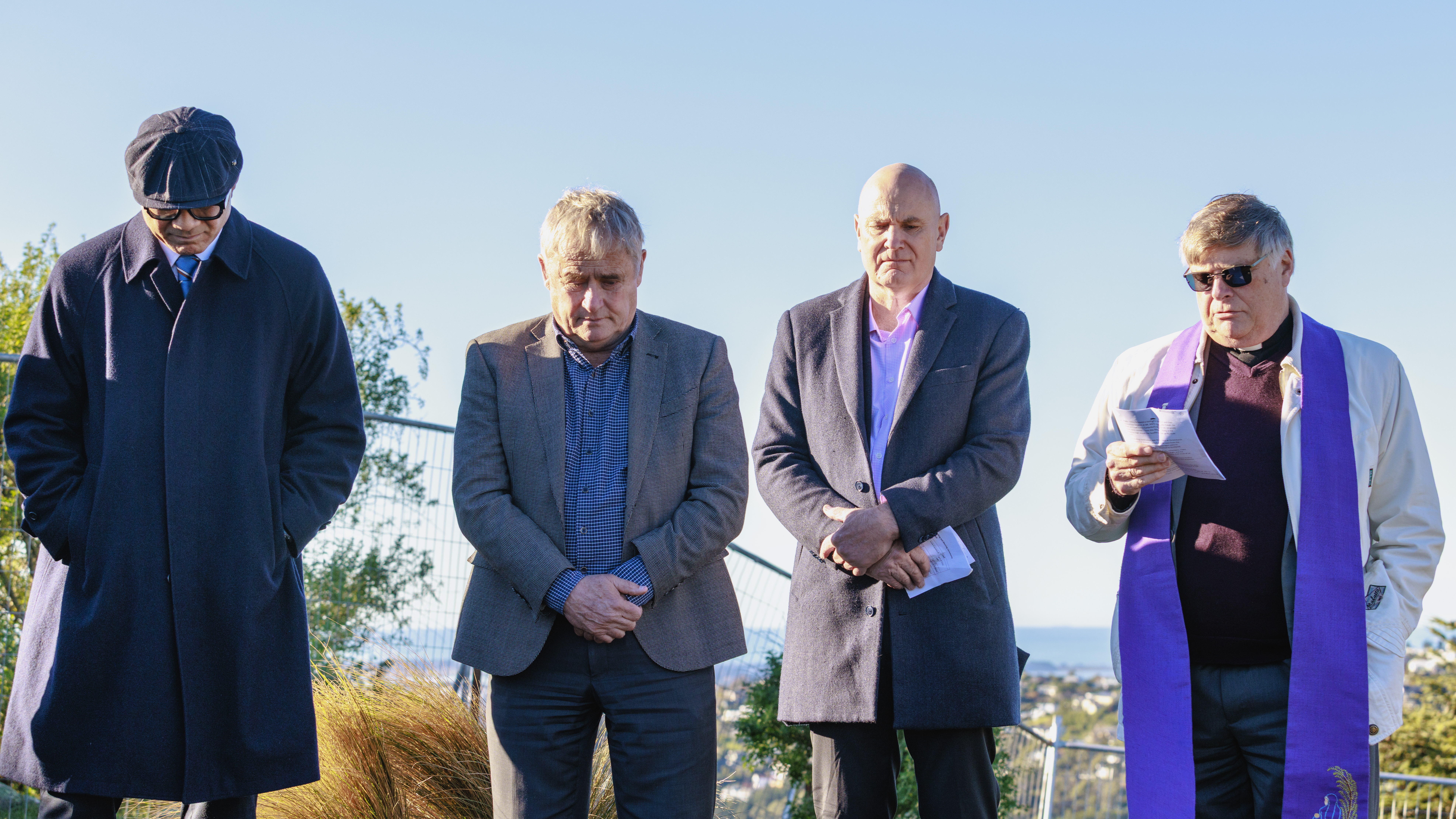 Four men including priest in prayer at blessing ceremony
