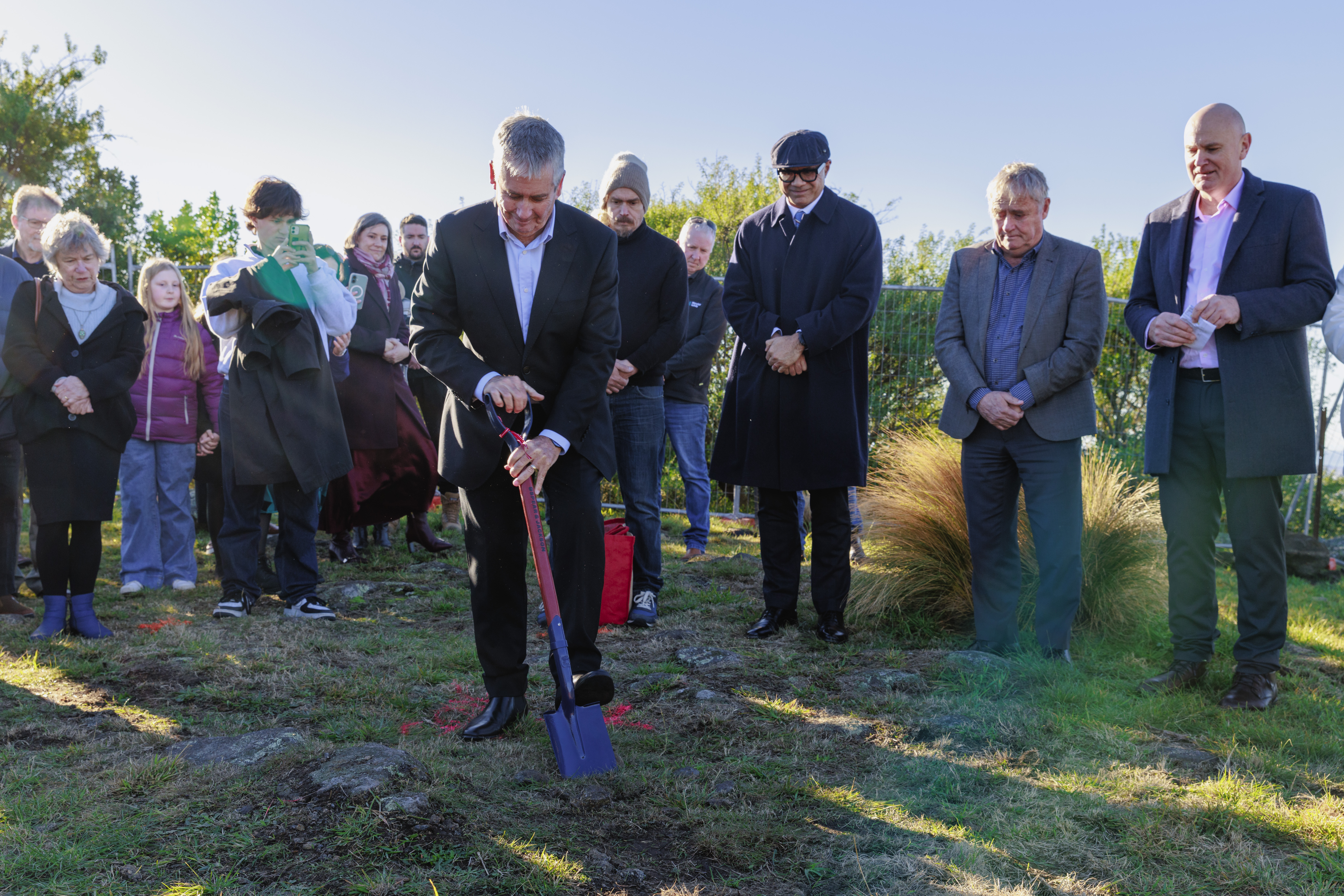 Group with one man holding spade at front with heads bowed in prayer