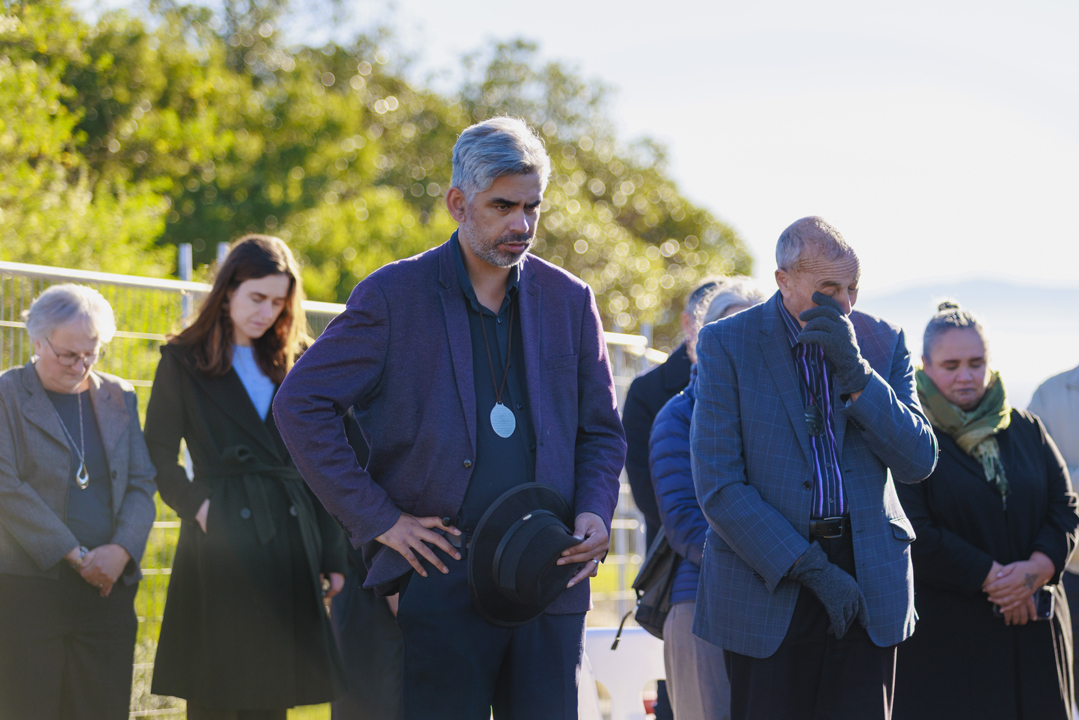 People standing listening to man speaking at blessing ceremony