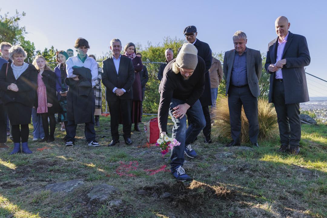 Man laying flowers on site at blessing ceremony
