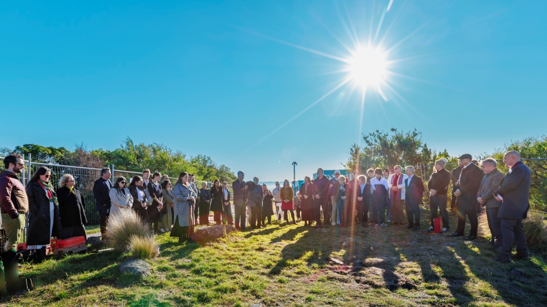 Crowd gathered in prayer on hill a sun rises in background