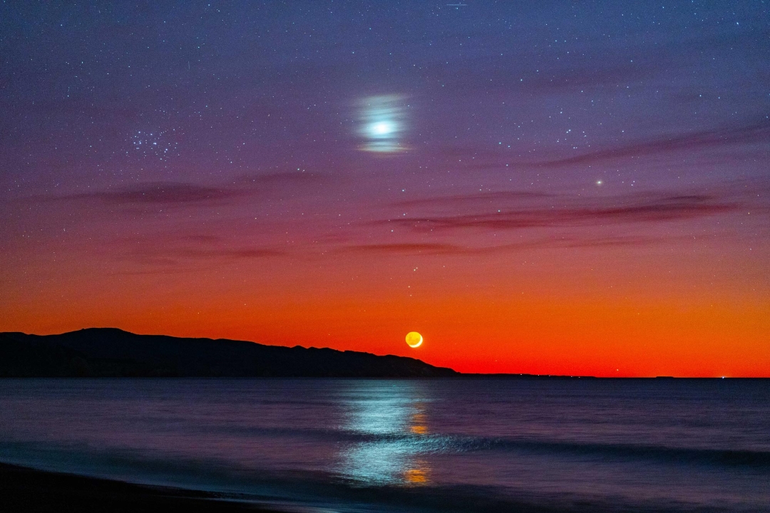 Star and sun in night sky over ocean