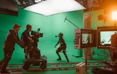 Movies set with camera on rails filming and actor against a green screent