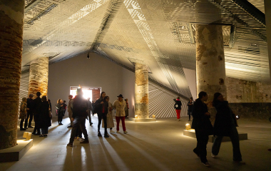 Visitors wandering around inside a modern whare-type building with light shining through slats in the roof