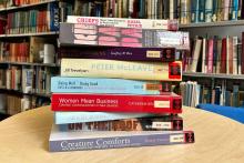 a stack of books on a table in a library. 