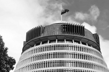Black and white image of NZ Flag half masted from the Beehive