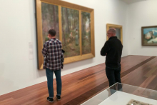 Two vistors standing in front of a large painting at a gallery