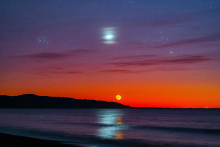 Star and sun in night sky over ocean